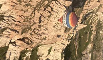 Hot air balloon flying over a rocky landscape.