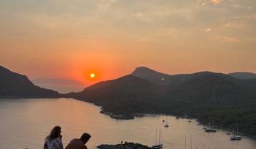 Sunset view over a bay with yachts and mountains.