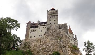 Bran Castle perched on a rocky hill with cloudy skies.