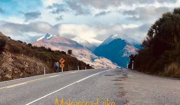 Road leading towards snow-covered mountains under cloudy skies.