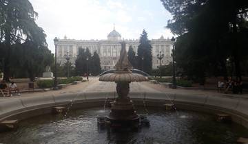 A fountain in a park in front of a grand historic building.