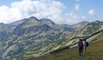 Hikers walking along mountain range with green vegetation.
