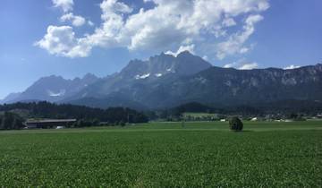 Green fields with mountain backdrop under a partly cloudy sky.