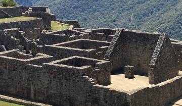 Ancient stone ruins with terraces and mountains in the background.