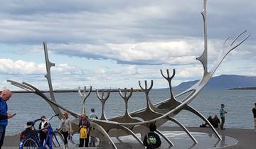 A metallic sculpture resembling a viking ship by the sea.