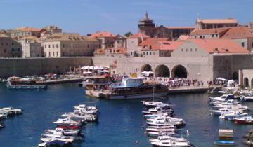 Harbor filled with boats against a historic stone wall.