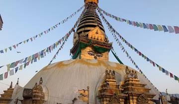 Buddhist stupa with colorful prayer flags against a clear sky.