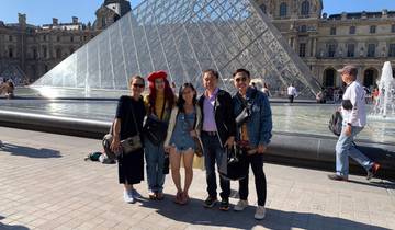 Group of people posing in front of the glass pyramid at the Louvre.