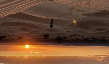 Sunset over expansive sand dunes.