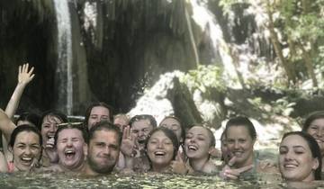 Group of people in a water pool with a waterfall in the background.