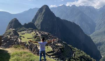 Person with arms outstretched enjoying the view of Machu Picchu.