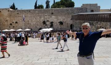 Man posing with arms outstretched in front of the Western Wall.