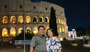 Couple posing in front of the Colosseum at night.