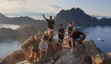 Group of people on top of a hill with ocean and islands behind them.