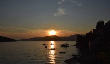 Sunset view over a calm water body with anchored boats.