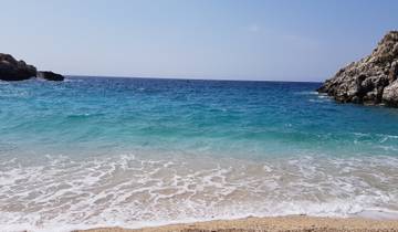 Clear blue ocean waves crashing on a sandy beach.