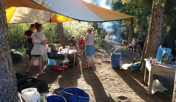 Outdoor campsite with people under a tent.