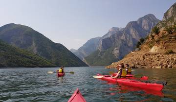 Kayakers in red kayaks exploring a scenic mountain lake.