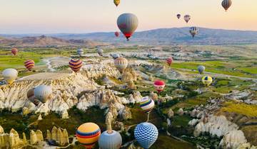 Hot air balloons over rocky landscape at sunrise