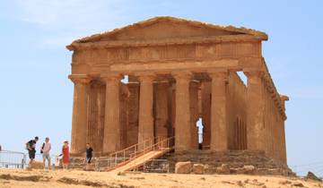 A historic temple with classic columns and tourists in the foreground.