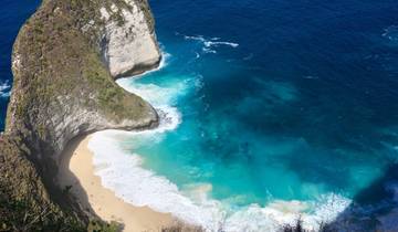 Aerial view of a beach with clear turquoise water and a dramatic cliff.
