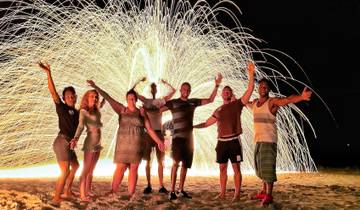Group enjoying a fire show on the beach at night.