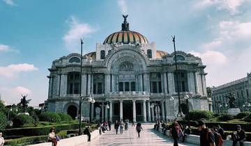 A grand building with a dome and statues in an urban park setting.