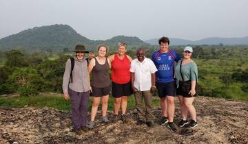 Group of six people standing on a rocky platform with a scenic backdrop.