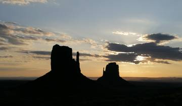 Silhouetted rock formations at sunset in Monument Valley.