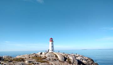 Lighthouse on rocky coast under a clear sky.