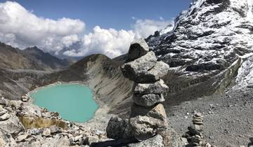Stacked stones by a turquoise glacial lake in the mountains.
