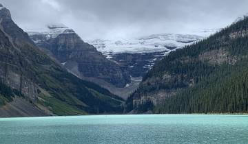Turquoise lake with snow-capped mountains in the background.