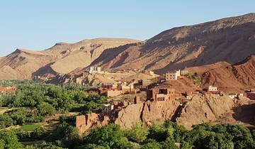 A picturesque village built into a hillside with green and rocky scenery.