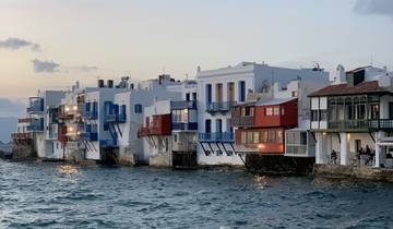 Seaside view with colorful buildings and waves crashing against the shore.