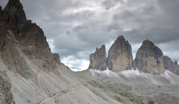 Dramatic view of the Tre Cime di Lavaredo mountains with a cloudy sky.