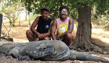 Two people posing with a large Komodo dragon.