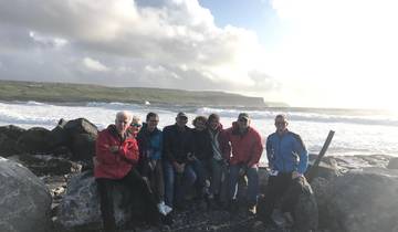 Group posing by a rocky shore with waves crashing behind.