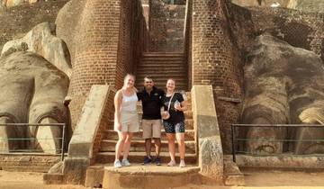 Tourists posing at the entrance of a historic site with large lion paws.