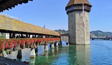 Historical wooden bridge with flowers over a river.