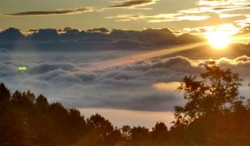 Sunrise over a cloud-filled valley with distant mountain peaks.
