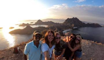 Group of friends posing on a hill overlooking stunning seascape.