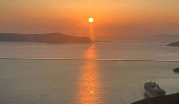 Sunset over a calm sea with a silhouette of land.