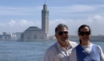 Couple posing in front of a mosque by the water.