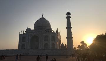 Silhouetted Taj Mahal at sunrise with people in foreground.