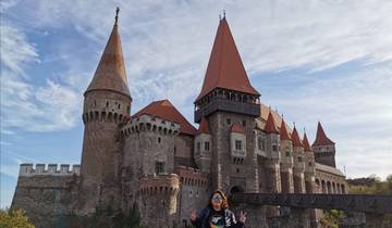 A person standing in front of a large castle with multiple towers.