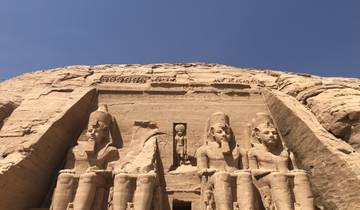 Ancient statues carved into a rock face in the desert.