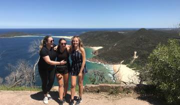 Three friends smiling on a cliff with ocean views.