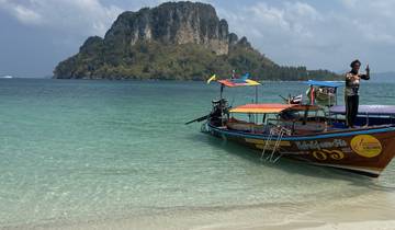Longtail boats anchored along a tropical beach with clear water.