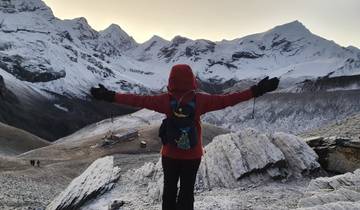 A single hiker with outstretched arms in front of snow-capped mountains