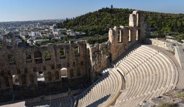 An ancient amphitheater overlooking a cityscape with green hills in the distance